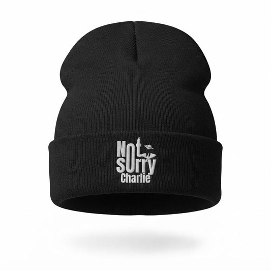 A black knit beanie hat with a white embroidered text graphic on the front cuff reading 'Not Sorry Charlie' with a small bird silhouette, shown on a clean white background.