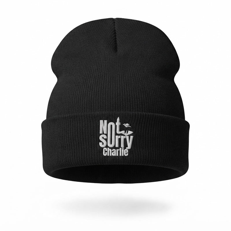 A black knit beanie hat with a white embroidered text graphic on the front cuff reading 'Not Sorry Charlie' with a small bird silhouette, shown on a clean white background.